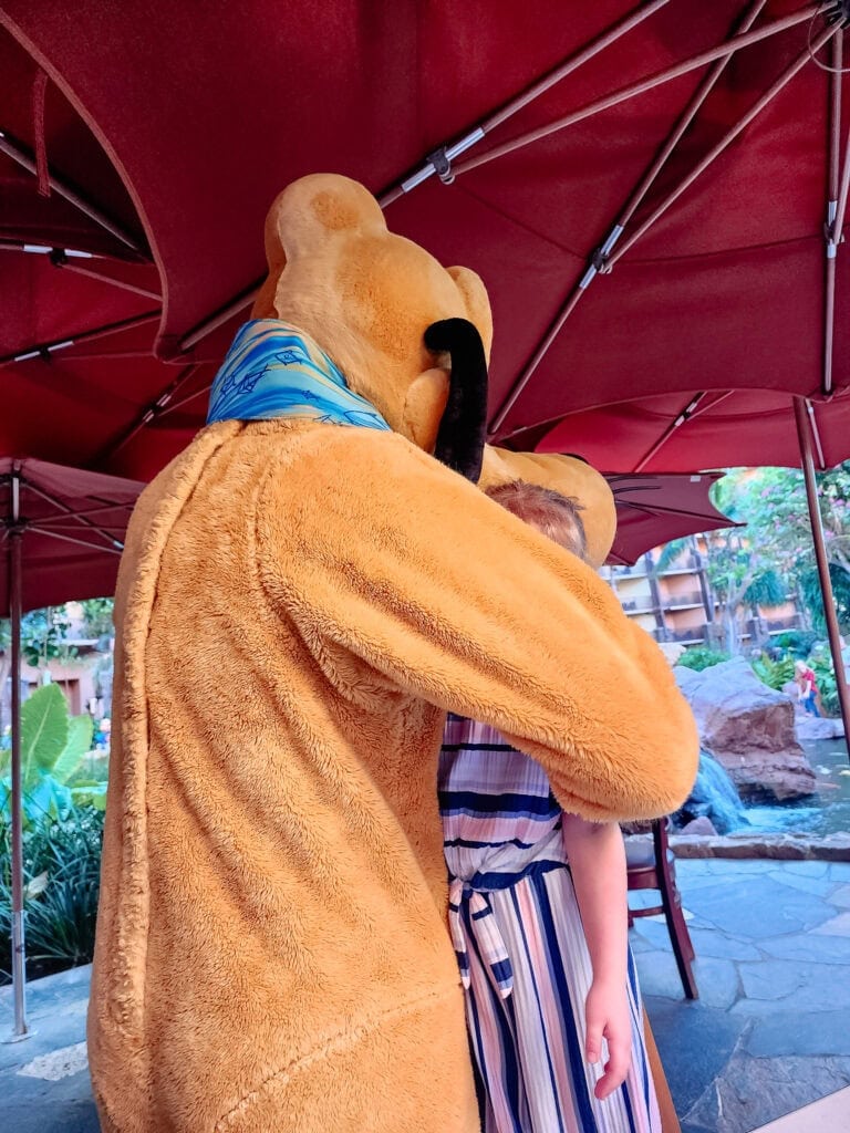 Pluto hugging little girl at Makahiki Restaurant in Disney's Aulani Resort.