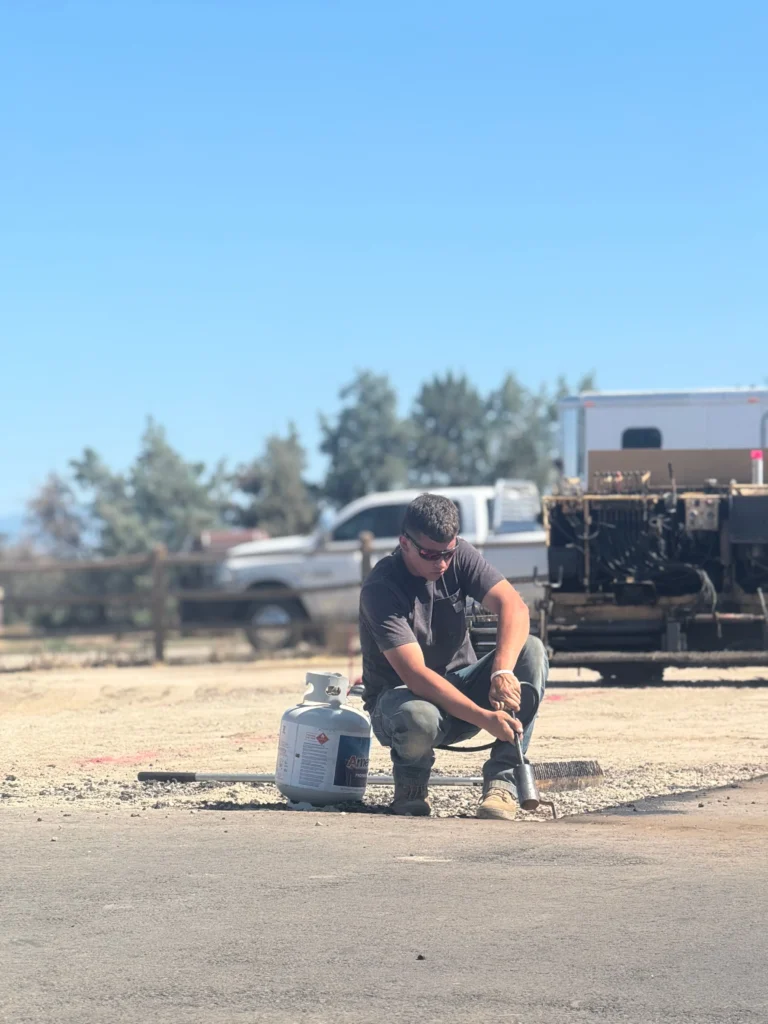 Worker using propane torch to repair asphalt cracks