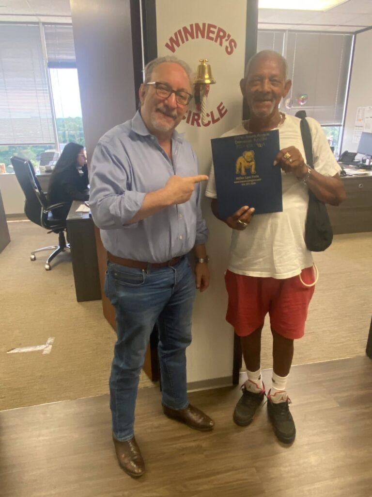 Justice served — client celebrates at The Miller Law Firm’s Winner’s Circle wall.