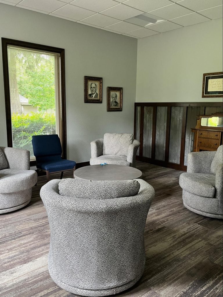A small seating room with five well-cushioned chairs, a coffee table, and various decorations. Good for a small group to talk.