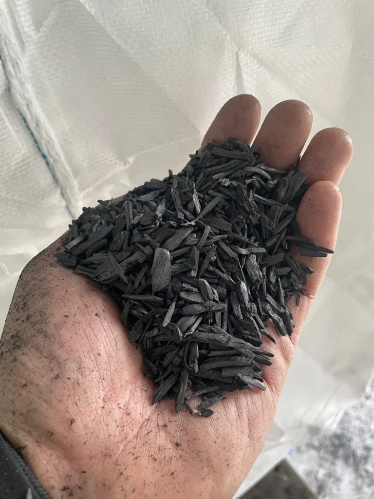 A hand holding small granulate biochar.