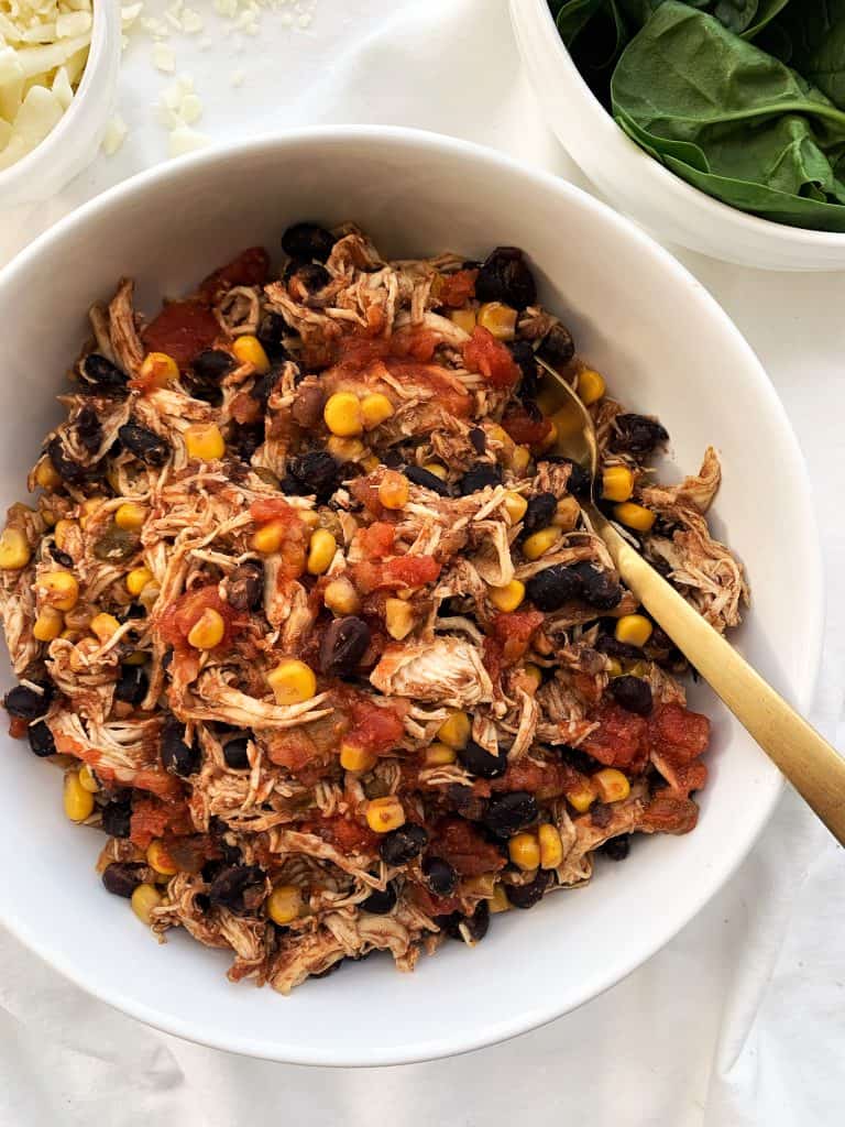 overhead shot of crockpot tex mex chicken with a gold spoon in a white bowl