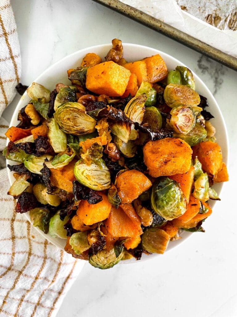top view of fall roasted veggies in a white bowl next to a towel