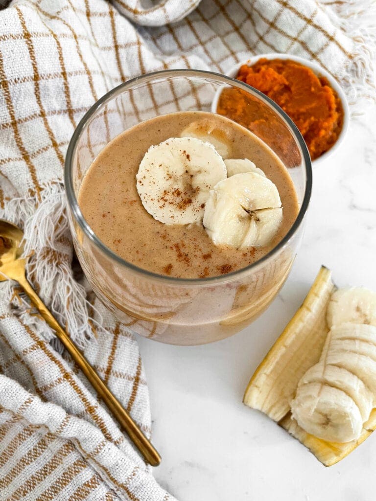 pumpkin protein shake in a glass next to a spoon