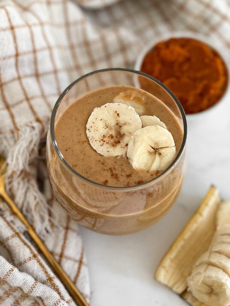 pumpkin protein shake in a glass topped with sliced bananas