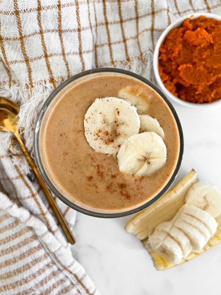top view of a homemade protein shake next to sliced bananas and pumpkin puree