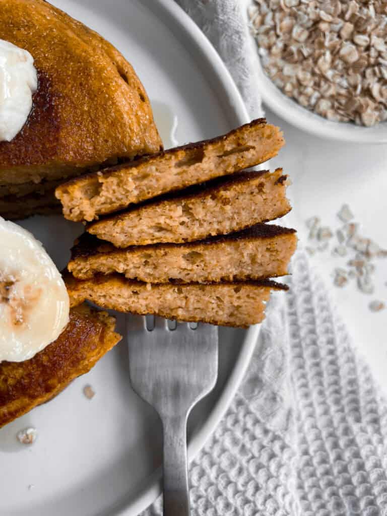 A stack of cottage cheese pumpkin pancakes with a bite on a fork.