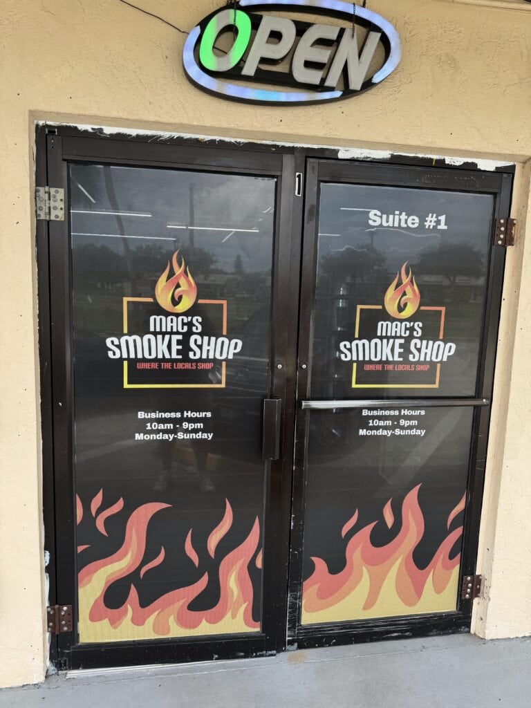 Mac's Smoke Shop window graphics and open sign. Business hours 10 AM to 9 PM, Monday to Sunday.