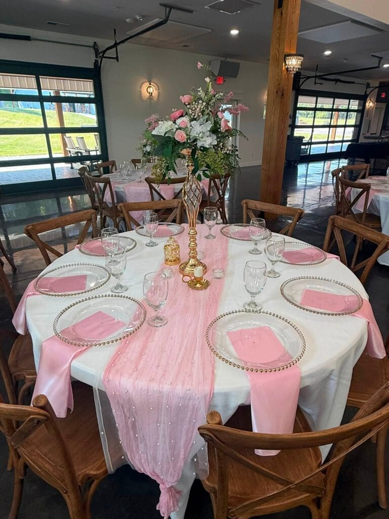 Reception hall round tables set with pink linens and floral centerpieces at Romaine Valley in Fenton, MO