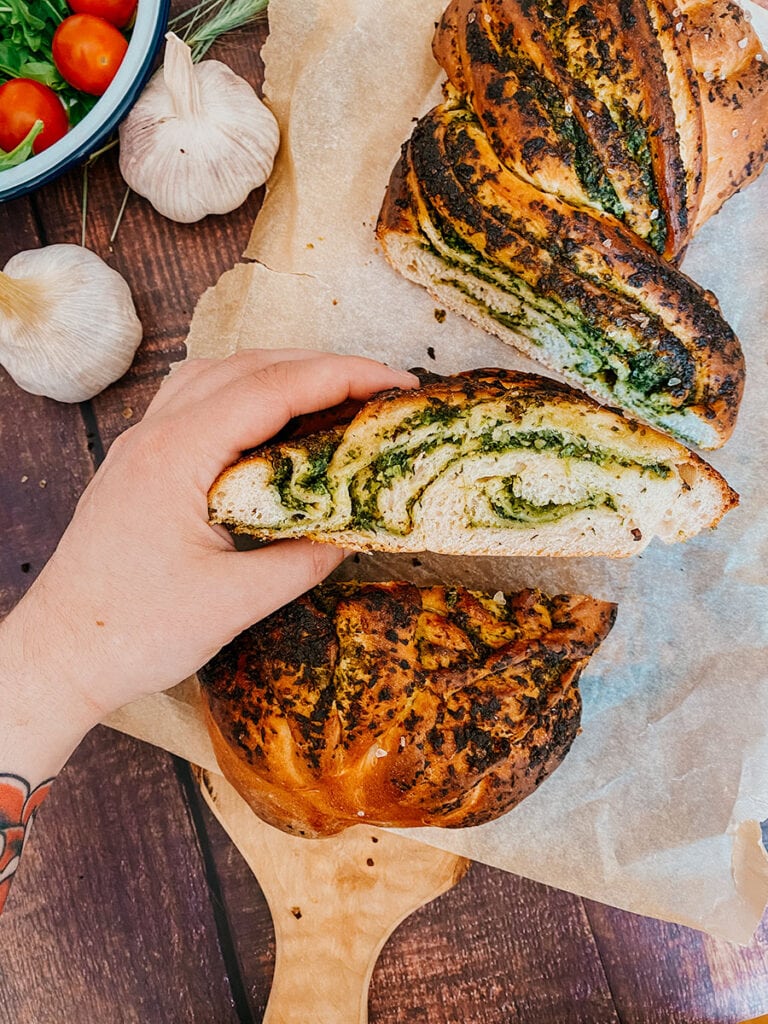 Wild Garlic Bread Braided with Homemade Pesto 7 close up of garlic loaf, garlic bread on, garlic and tomatoes on the side, on a wooden background