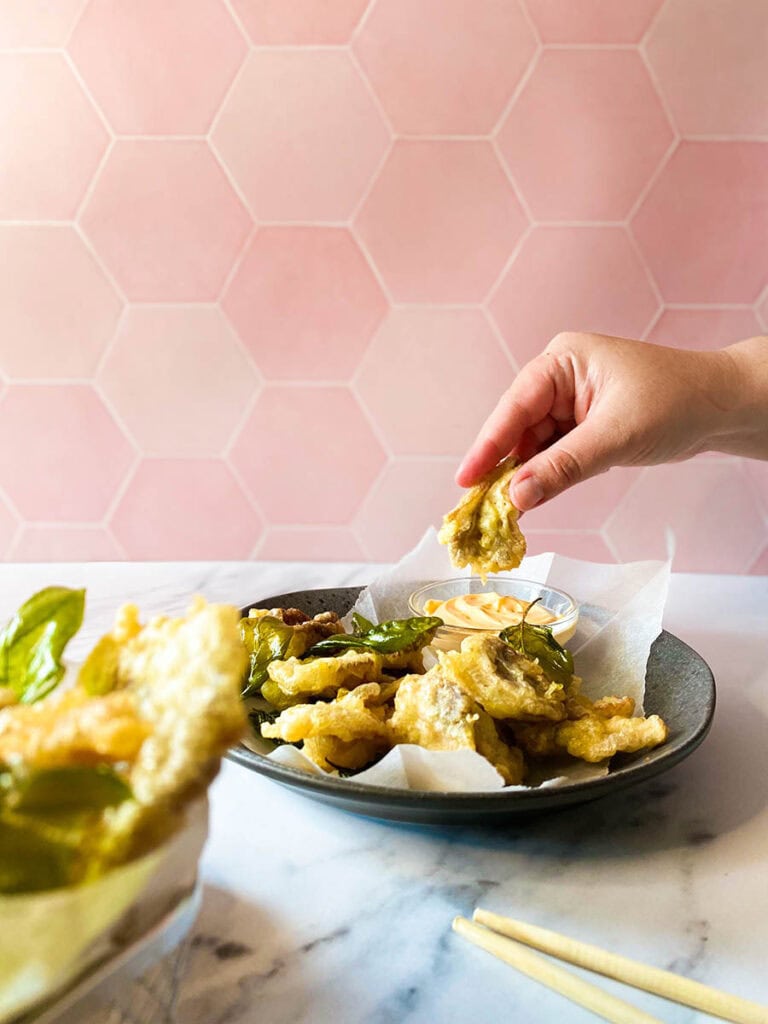 The #1 Best Popcorn Mushroom Recipe, Taiwanese-style 8 popcorn mushroom in a silver basket over some parchment paper, with extra dark dish and mushrooms on the background