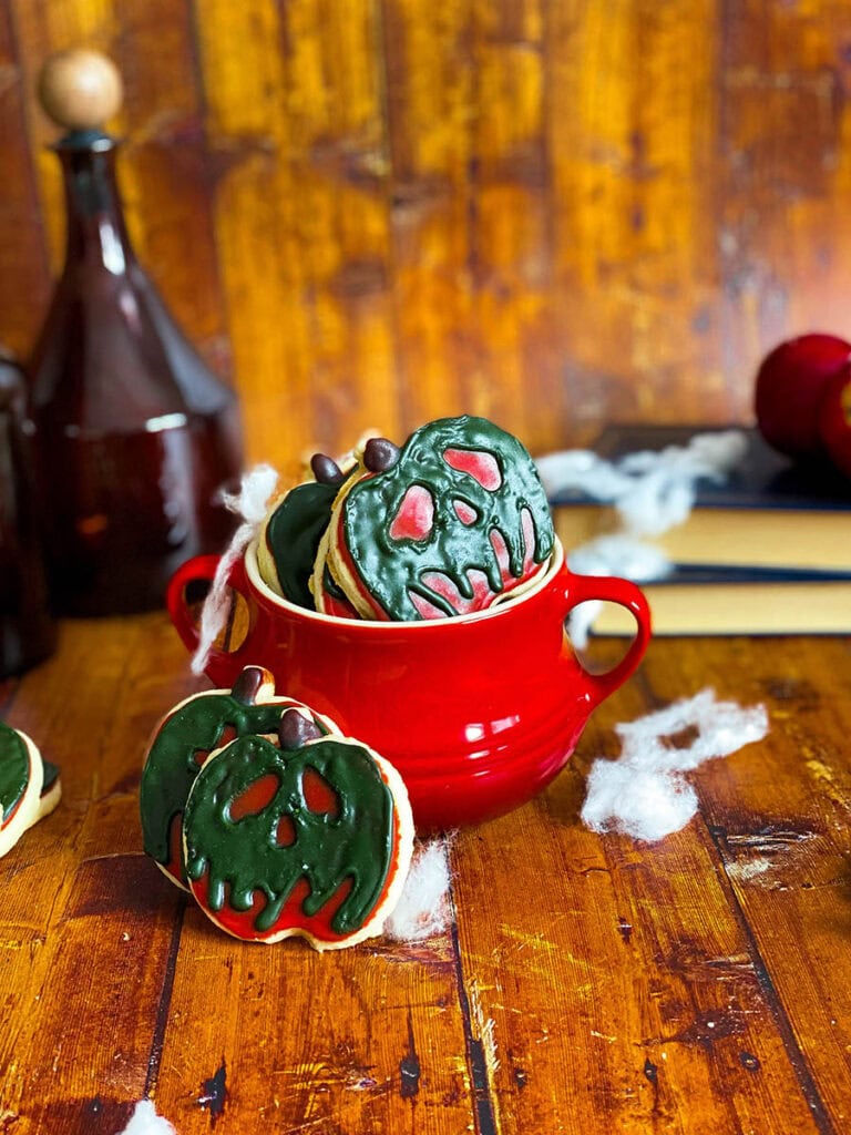 poison apple cookie in a red cauldron with some spiderwebs scattered across, some poison bottles and books