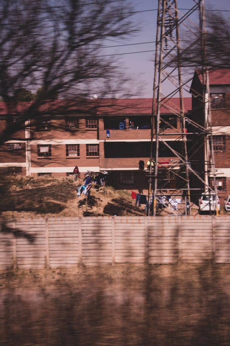 A blurred urban residential scene featuring laundry and power lines in Johannesburg.