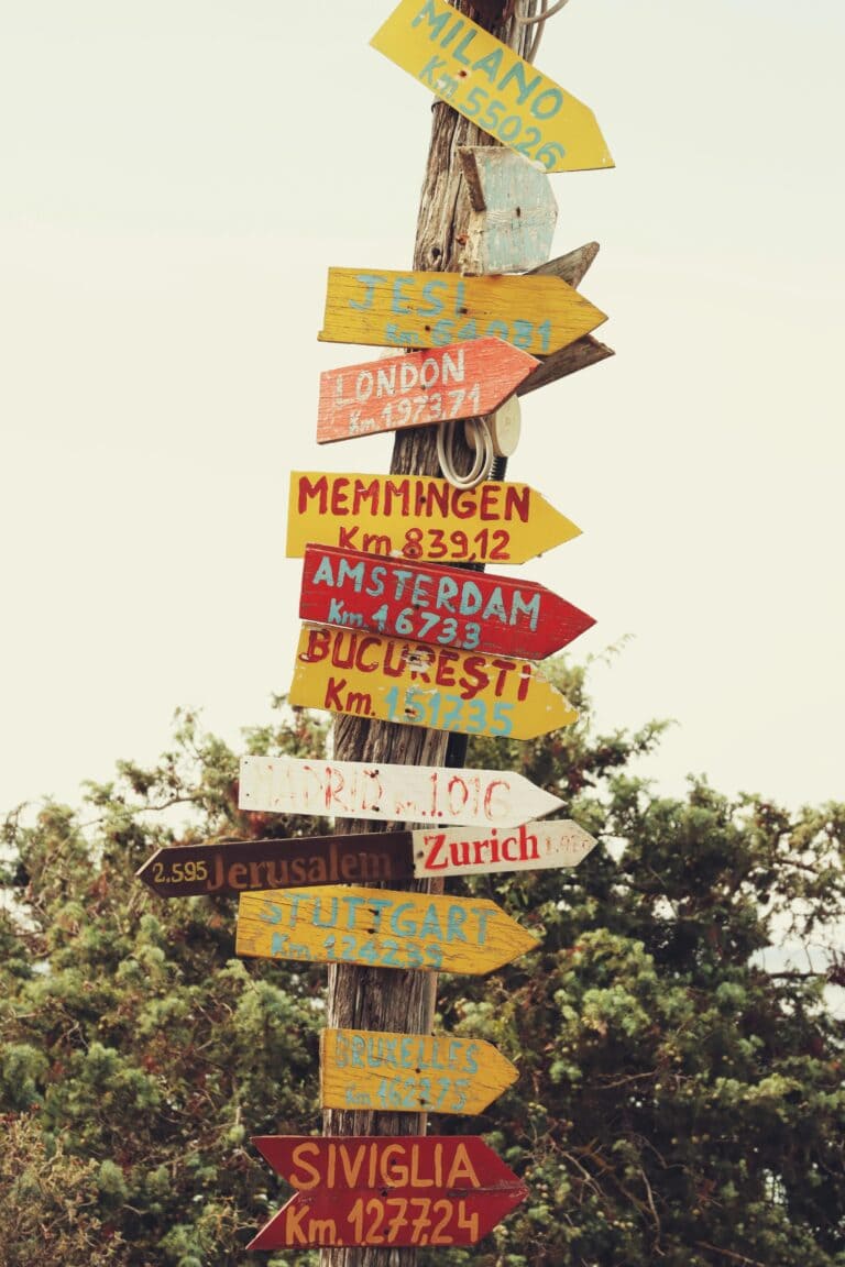 A vertical shot of a colorful direction signpost in Alghero, Sardinia, Italy.