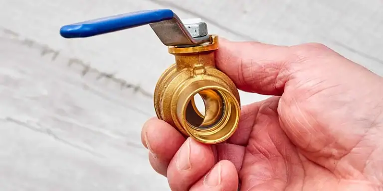 shut-off valve - Hand holding water shutoff valve - man holding blue handled ball shut-off valve