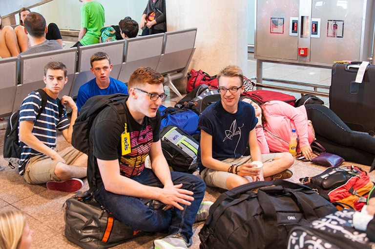 Students waiting at airport with luggage