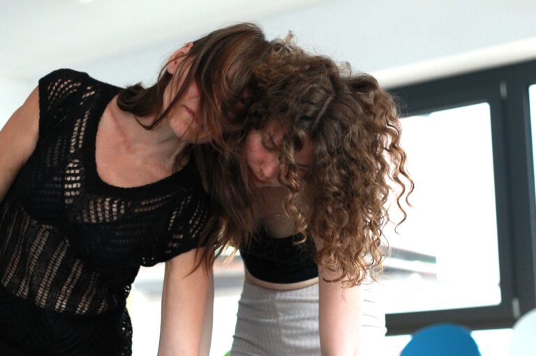 Zwei Frauen lehnen ihre Köpfe aneinander und bewegen sich gemeinsam nach vorne.