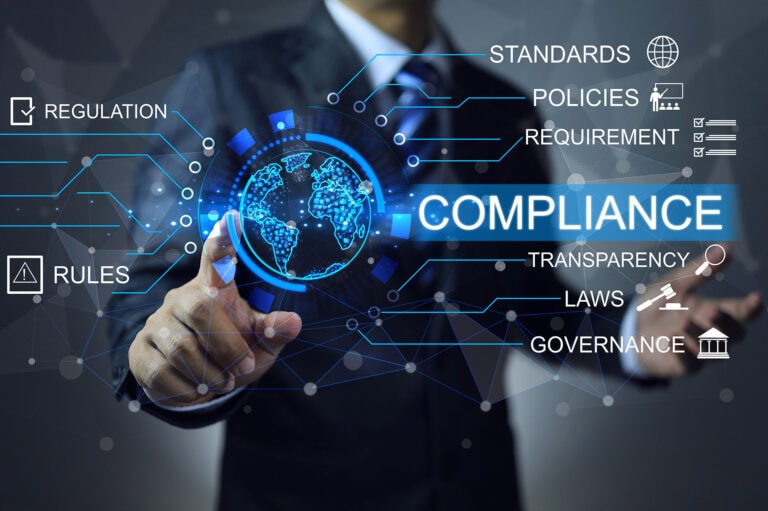 A man in business attire is touching the word compliance.