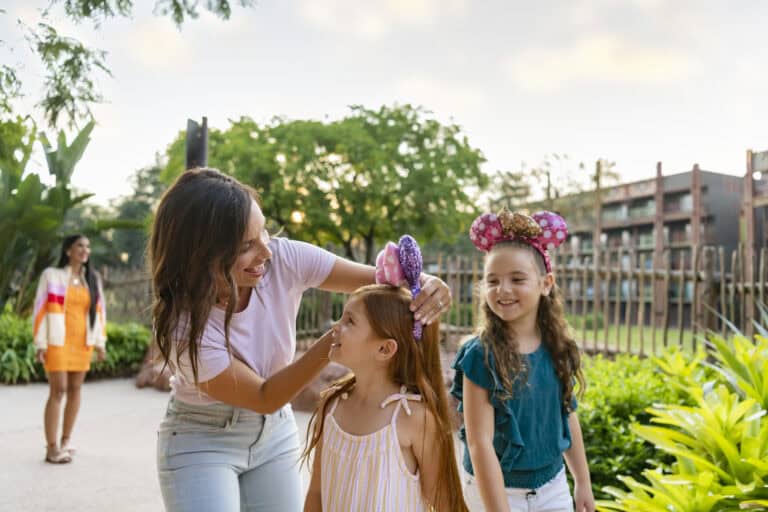 Family enjoying outdoor fun with children wearing Minnie Mouse ears and smiling.