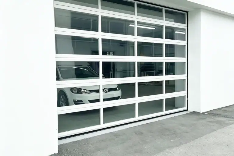A modern white commercial all-window sectional door with heavy-duty aluminum frames and clear vision panels, manufactured by ABX to maximize industrial daylighting for an automotive facility.