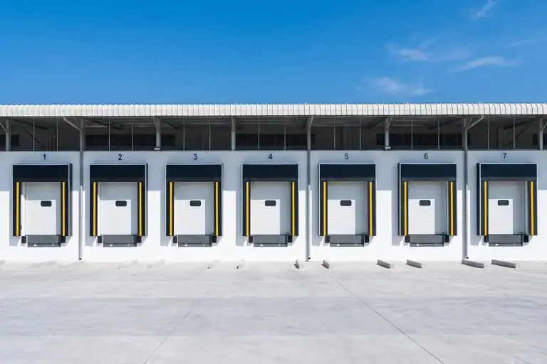 Row of heavy-duty insulated sectional doors equipped with dock seals at a modern cold storage facility, engineered to deliver K≤0.8W/m³.K thermal insulation for strict temperature-controlled logistics projects.