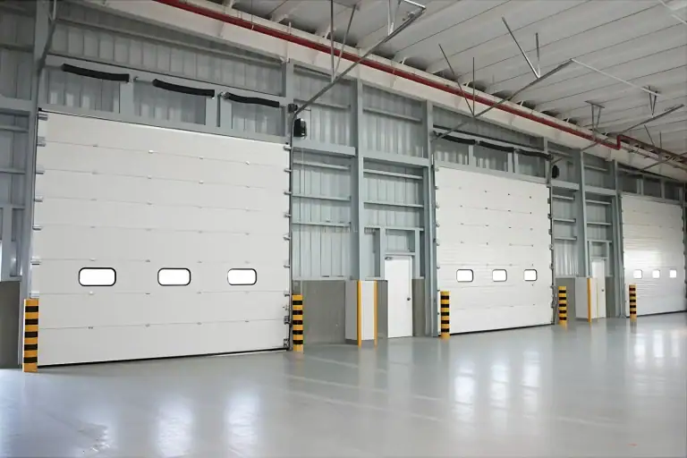 Interior installation view of multiple heavy-duty industrial sectional doors inside the XCMG manufacturing facility, engineered with vision windows and safety bollards for high-frequency automotive production environments.