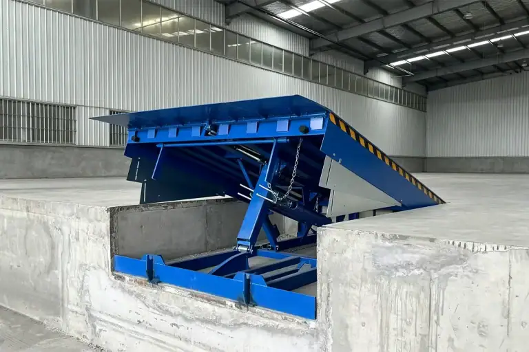 Heavy duty hydraulic dock leveler with safety guards installed in an industrial warehouse loading bay