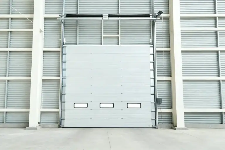 Modern industrial sectional overhead door with insulated panels installed in a large manufacturing warehouse