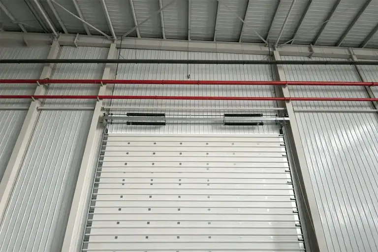 Interior view of a high-performance commercial sectional door featuring heavy-duty torsion springs, safety tracking, and thermal insulated panels inside an industrial warehouse.