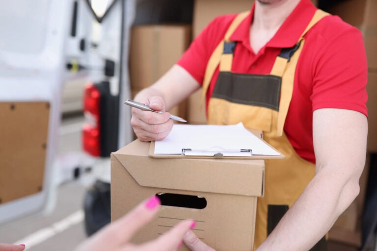 Courier gives pen to the client to sign on delivery receipt. Receive a parcel from delivery service concept