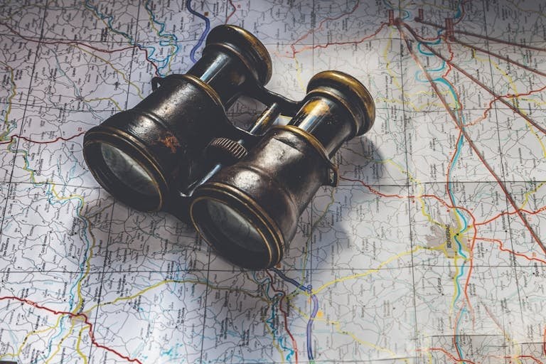 Close-up of antique binoculars placed on a detailed map, evoking adventure.