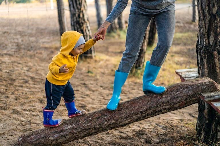 A small child reaching up to hold their parent's hand while climbing, symbolizing dependence and trust