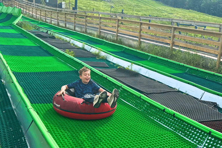 Little boy going down on a summer tubing in the family resort in quebec called Mont Tremblant