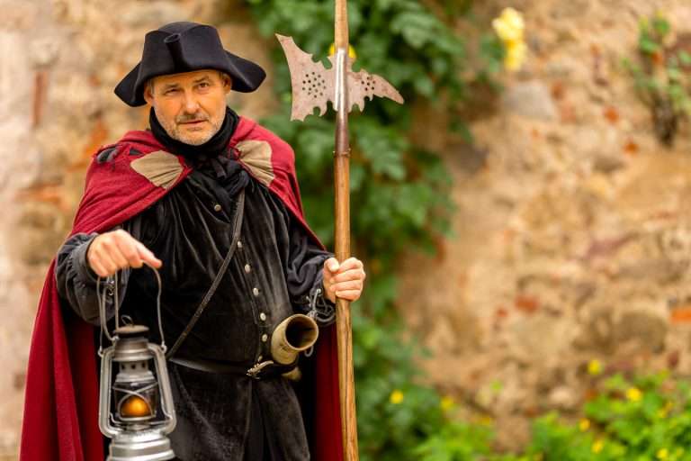 Ein verkleideter Schauspieler als historischer Nachtwächter Bertold VI. von Historix-Tours mit einer brennenden Laterne in den abendlichen Gassen der Altstadt von Freiburg im Breisgau.