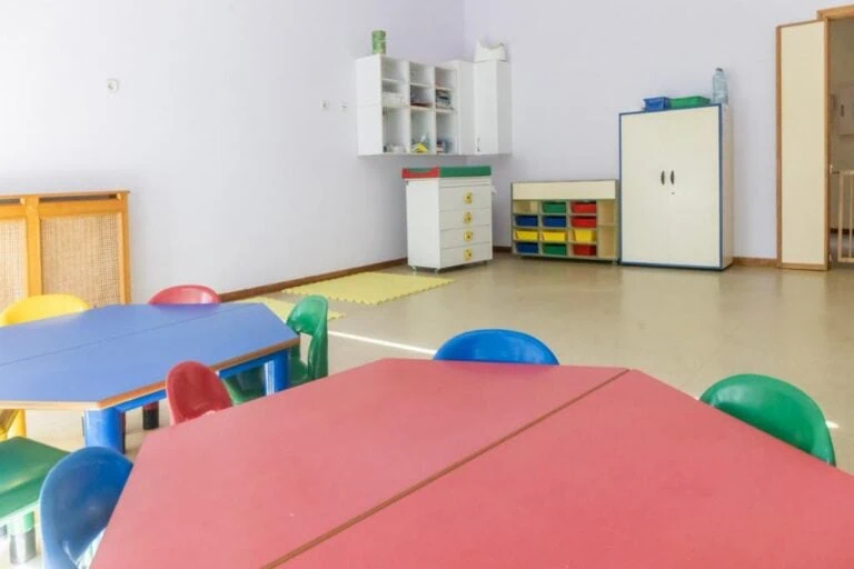 Aula de Educación Infantil vacía con mesas y sillas de colores, imagen de recurso