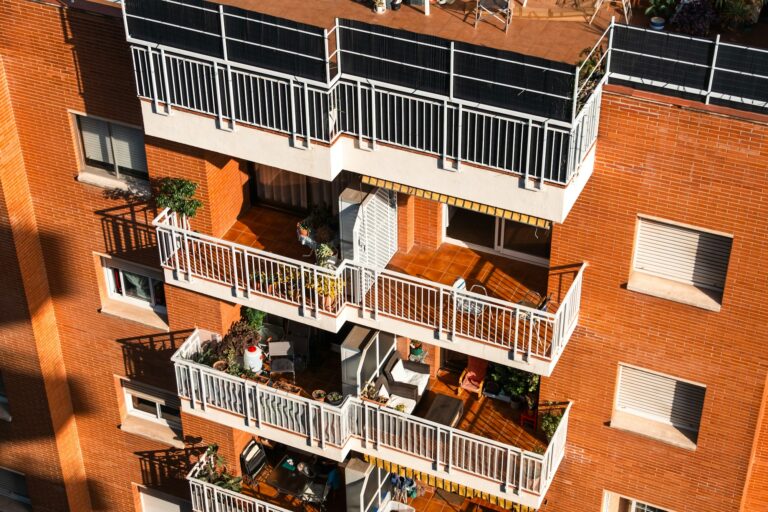 Bloque de viviendas de ladrillo rojo con balcones, imagen de recurso sobre el IBI en el Corredor del Henares