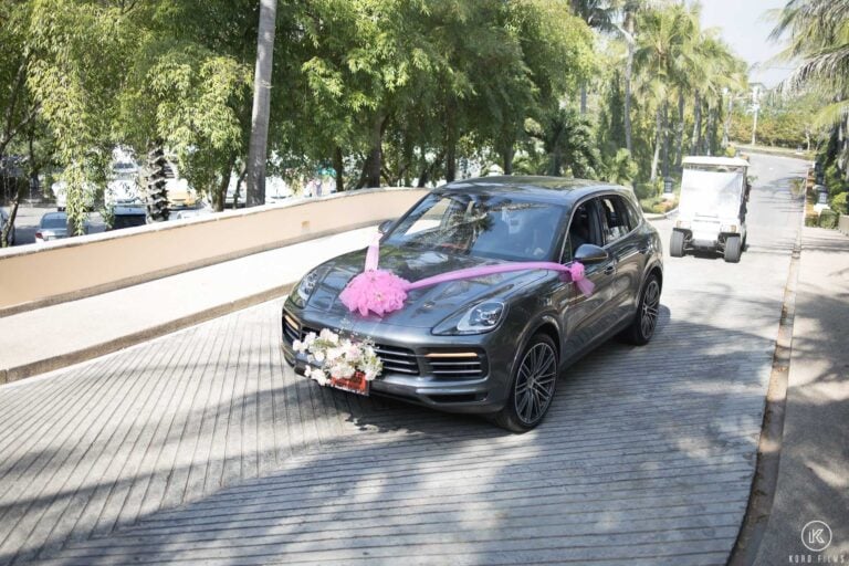 The wedding car with a pink ribbon and flowers on the driveway at Dusit Thani Hua Hin