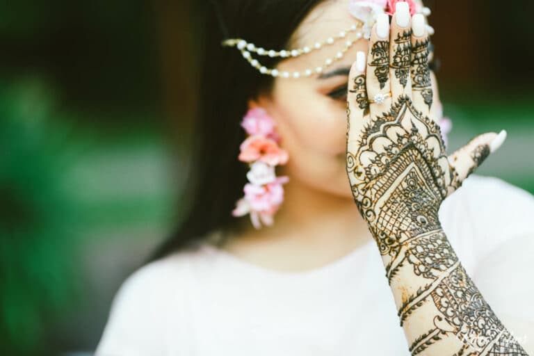 Close-up of the bride’s henna-covered hand and pink floral jewellery at her Mehendi in Pattaya