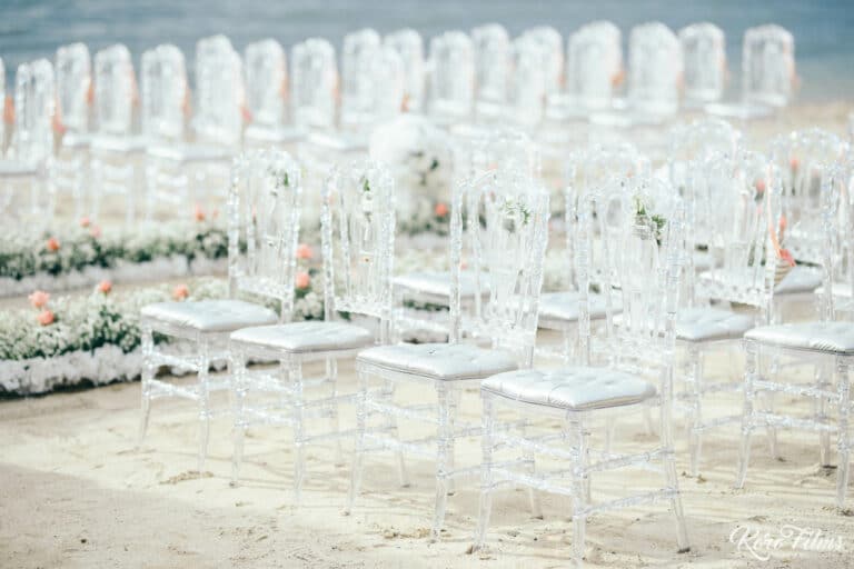 Rows of clear chairs and white flowers set up on the beach for the Nepali wedding ceremony at Cape Dara Resort