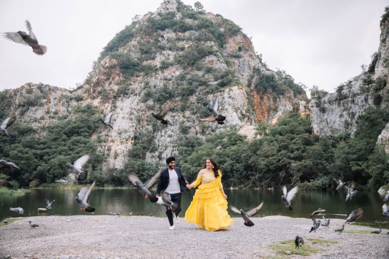Natasha in a yellow gown and Bakshdeep as birds fly up below the limestone cliffs of Khao Ngu, Ratchaburi