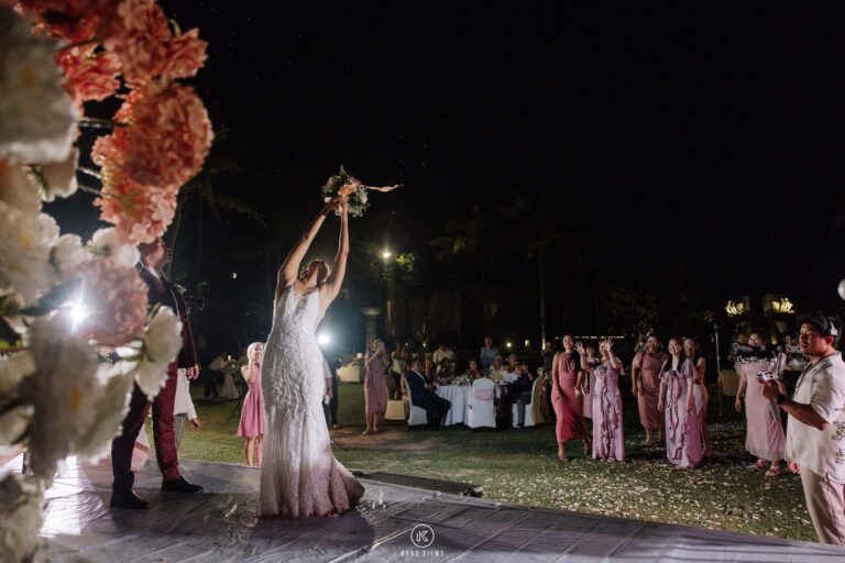 The bride throws her bouquet at the night-time wedding reception at Sheraton Hua Hin