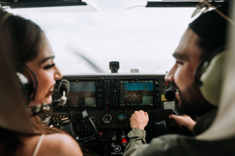 Ritu and Naveen in aviation headsets laugh in the cockpit of a light aircraft