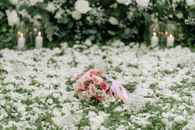 Pink rose bouquet with a ribbon resting on white flowers at the proposal set-up in Hua Hin