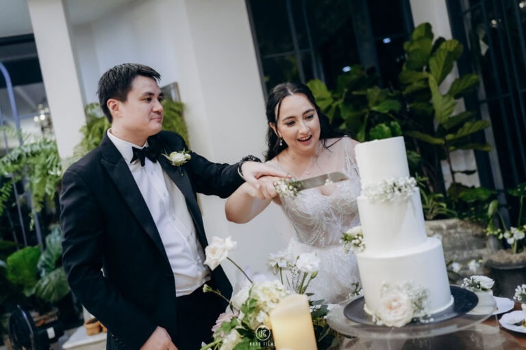 Tara and Alastair cut their three-tier white wedding cake at The Botanical House, Bangkok