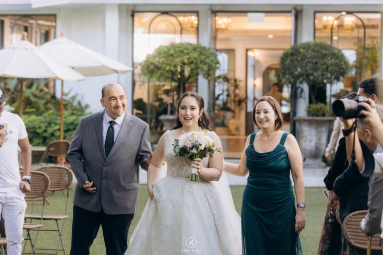 The bride walks to her garden ceremony with family beside her at The Botanical House, Bangkok