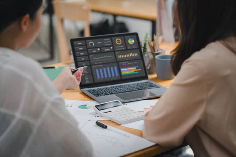 two nonprofit workers looking at their funds on a laptop using fund accounting software