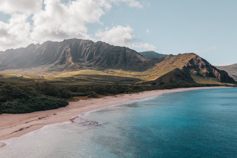 Breathtaking aerial shot of Hawaii's pristine coastline with mountains and ocean. Featured image for which hawaiian island is the best to visit post.