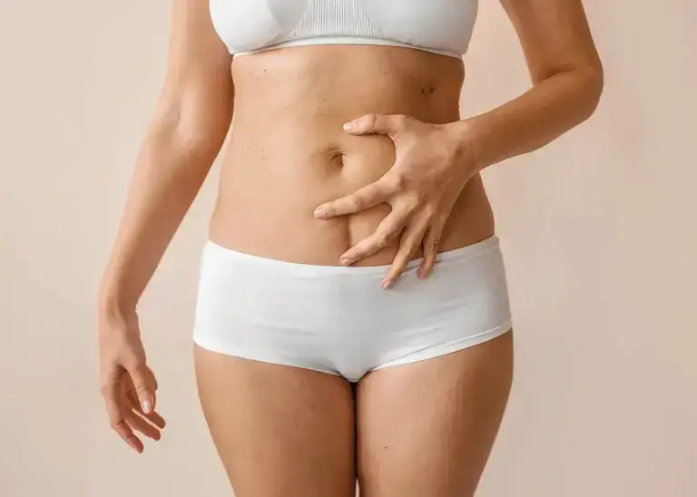Woman resting a hand on her abdomen, liposuction in Dallas