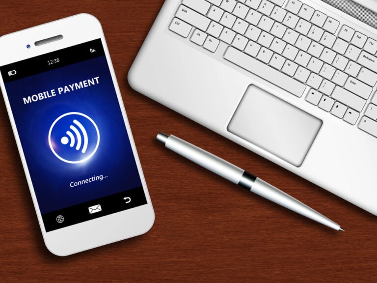 Mobile phone displaying "Mobile Payment" text above a tap-to-pay logo next to a laptop computer