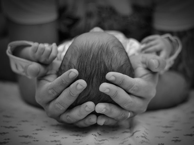 Parent gently holding a newborn representing the hidden mystery of biblical sonship